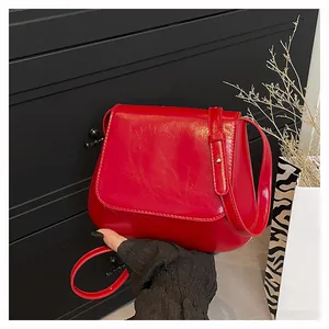 Close-up of a glossy red leather flap shoulder bag with adjustable strap details