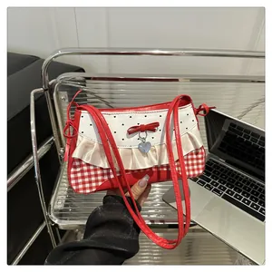 Detail der rot-weiß karierten Schultertasche mit Schleife, Herzanhänger und Rüschen