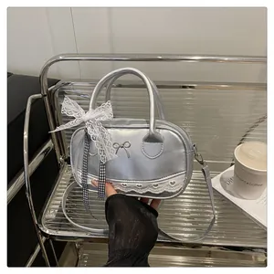 Dettaglio della borsa Boston argento metallizzato con pizzo bianco e ciondolo a fiocco
