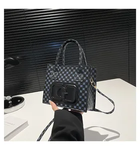 Detail of blue and black patterned tote bag with a large G logo and golden buckles