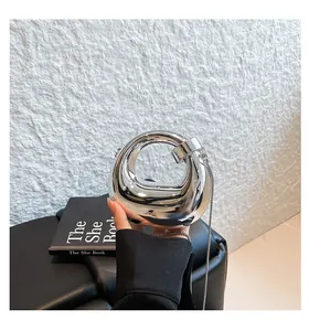 Detail of silver mirror acrylic mini handbag featuring a circular ring handle and chain