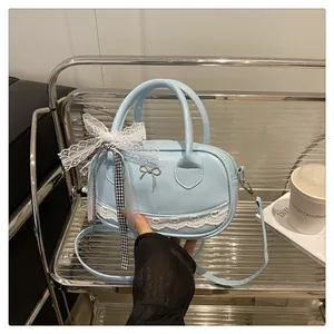 Dettaglio borsa Boston azzurra con bordo in pizzo a cuore bianco e fibbia a fiocco argento