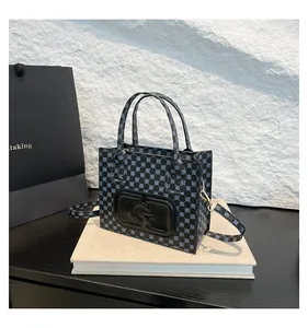 Close-up of printed square tote bag with G letter logo and gold hardware detail