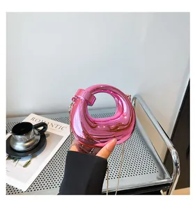 Detail of metallic pink mini bag featuring unique geometric cutout and gold chain strap