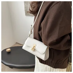 Detailed close-up of white PU leather crossbody bag with golden metal twist lock and knot strap