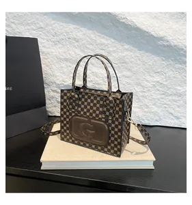 Detail of vintage patterned square tote bag featuring a leather G logo and detachable strap