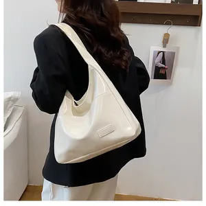Dettaglio di una borsa hobo bianca lucida con ampia tracolla per un look sofisticato