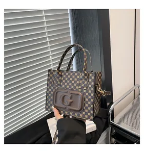 Detail of a brown monogram handbag with an embossed letter G and a detachable shoulder strap