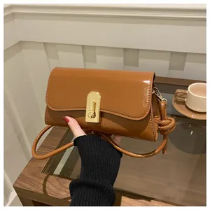 Detail of brown leather shoulder bag with gold oval clasp and knotted strap design