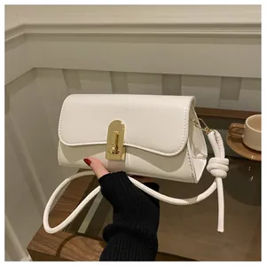 Detail of minimalist cream faux leather handbag with gold metal clasp and knotted strap