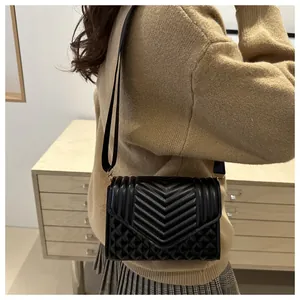 Detail van een zwarte gewatteerde crossbodytas met chevronpatroon en brede band