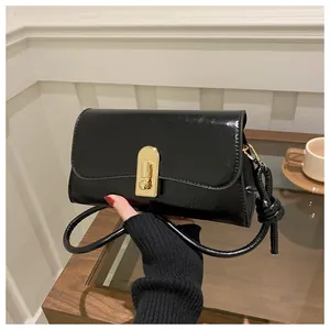 Detailed close-up of glossy black leather bag featuring a gold horseshoe metal clasp