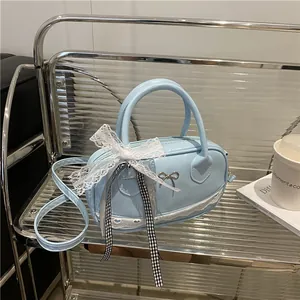 Borsa Boston celeste in ecopelle con pizzo e fiocco in metallo su uno scaffale