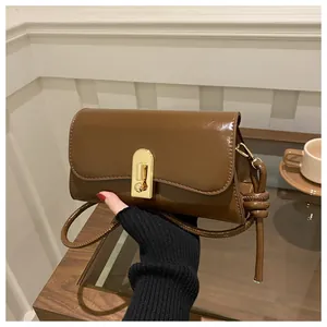 Detail of vintage brown baguette bag with golden metal buckle and knot strap detail
