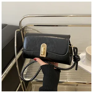 Detail of vintage black baguette bag featuring textured leather and gold buckle clasp