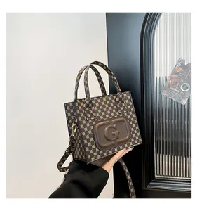Close-up of vintage printed tote bag with brown leather G-logo plaque and gold hardware