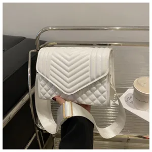 Detail van witte gewatteerde crossbodytas met V-patroon en brede stoffen schouderriem