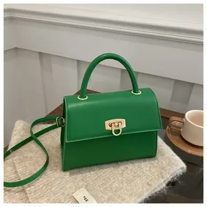 Detailaufnahme der grünen Ledertasche mit goldenem Drehverschluss auf Strickstoff