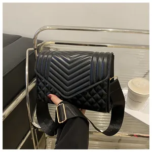 Detail van V-stiksel en ruitvormige textuur op zwarte leren crossbodytas met schouderband