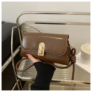 Close-up of vintage brown gloss leather bag with large gold oval metal twist lock detail