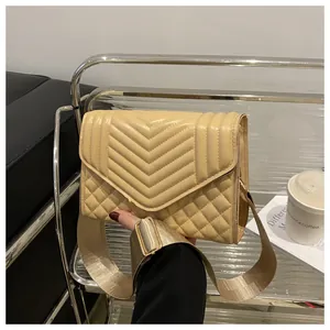 Detail van beige gewatteerde crossbodytas met brede canvas riem en gouden metalen gespen