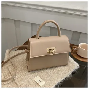 Detail einer khakifarbenen Ledertasche mit goldenem Verschluss und Schultergurt