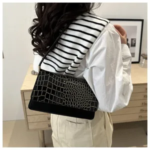 Detail of black crocodile embossed baguette bag with golden edge lining on leather scales