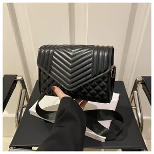 Detail van zwarte gewatteerde crossbodytas met V-stiksels en goudkleurige metalen gespen