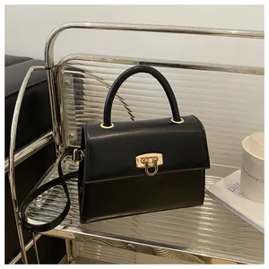 Detailansicht der schwarzen Lederhandtasche mit elegantem goldenem Metallschloss auf Ständer