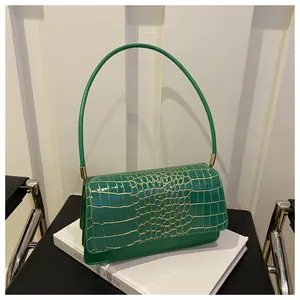 Detail of green crocodile embossed shoulder bag on white stand with retro style