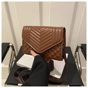 Detail van bruine gewatteerde crossbodytas met een stijlvolle brede stoffen schouderriem