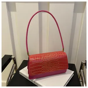 Detail of pink faux crocodile texture handbag on books with elegant gold metal hardware