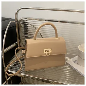 Detail der beigen quadratischen Tasche mit goldenem Drehverschluss und rundem Griff