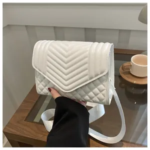 Detail van de witte gewatteerde crossbodytas met V-stiksels en een brede stoffen schouderband