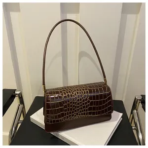 Detail of dark brown faux-crocodile shoulder bag with gold hardware and flap closure