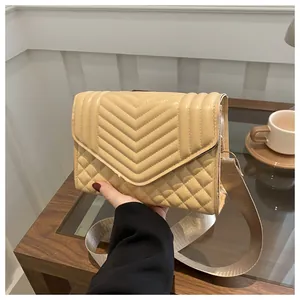Detail van de crèmekleurige gewatteerde crossbodytas met v-patroon en brede schouderband
