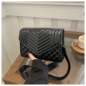 Detail van zwarte crossbodytas met V-vormige stiksels, ruitpatroon en brede schouderband