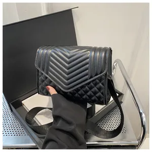 Macro-opname van V-vormig stiksel en ruitpatronen op een zwarte leren crossbodytas