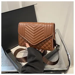 Detailopname van de bruine gewatteerde crossbodytas met V-patroon en ruitvormig stikwerk