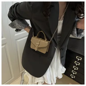 Detail of a khaki mini square bag with a gold U-shaped buckle and metal chain strap
