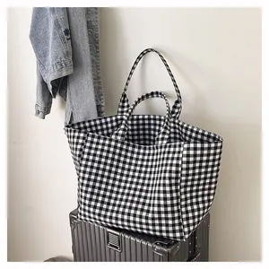 Détail du sac cabas à carreaux noir et blanc posé sur une valise argentée en décor