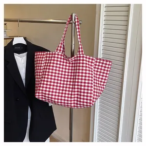 Détail d'un grand sac cabas en toile à carreaux vichy rouge et blanc sur un cintre