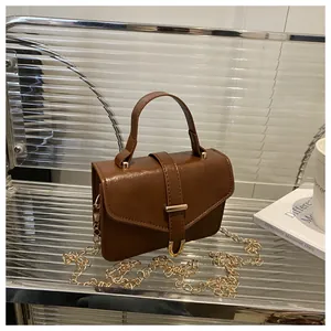 Detail view of brown vintage leather crossbody bag with gold chain and metal buckle
