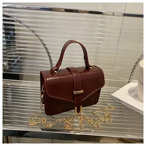 Detail of vintage reddish-brown crossbody bag with glossy leather and gold chain strap