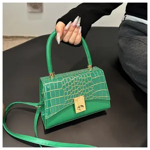 Detail der smaragdgrünen Handtasche mit Krokoprägung und elegantem goldenen Drehverschluss