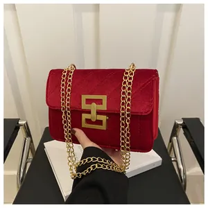 Detail of red velvet shoulder bag featuring luxury quilted texture and gold metal clasp