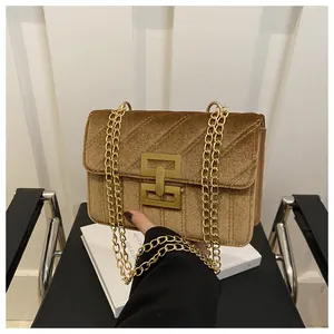 Detailed view of golden brown velvet crossbody bag with V-shaped quilting and metal lock