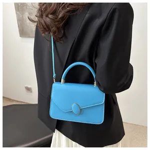 Blaue rechteckige Umhängetasche mit Metallschnalle an Model in schwarzem Blazer