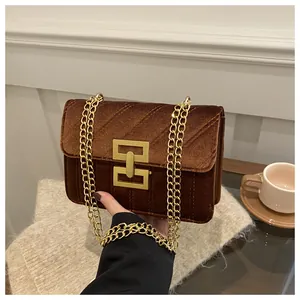 Detailed view of dark brown velvet quilted crossbody bag with golden chain and clasp