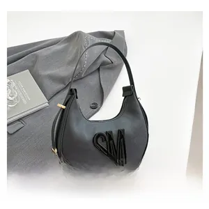 Detail view of black crescent bag with SM logo, lychee texture and gold buckle hardware